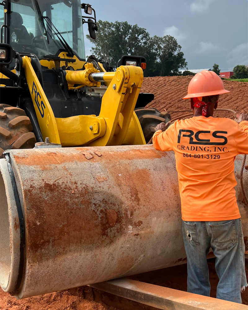 construction worker directing a drainage pipe laying